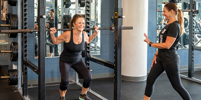 Personal trainer working with someone on weights