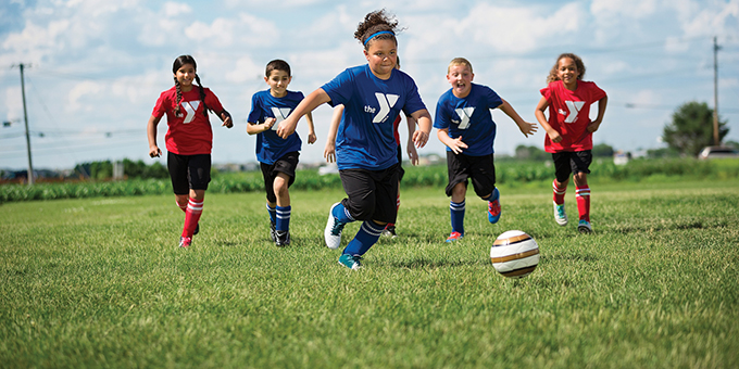 kids kicking  a soccer ball on a field