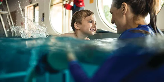 Little boy learning how to swim with instructor