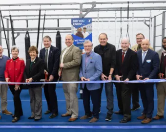 group of people cutting a blue ribbon