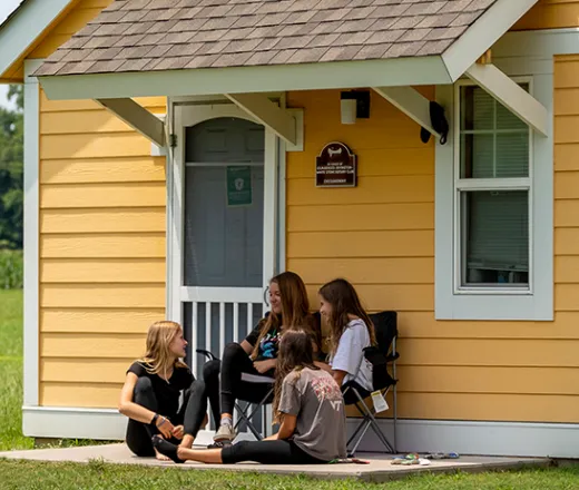 Girls sitting outside of a house talking at Camp Kekoka