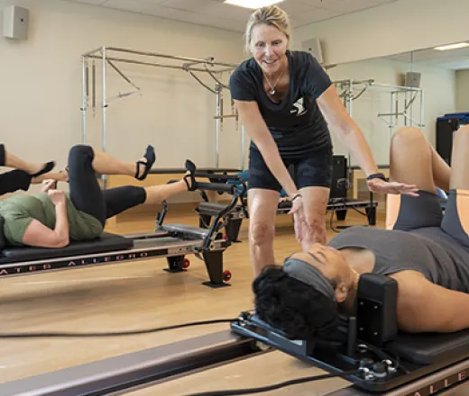 Instructor helping someone on a Pilates reformer