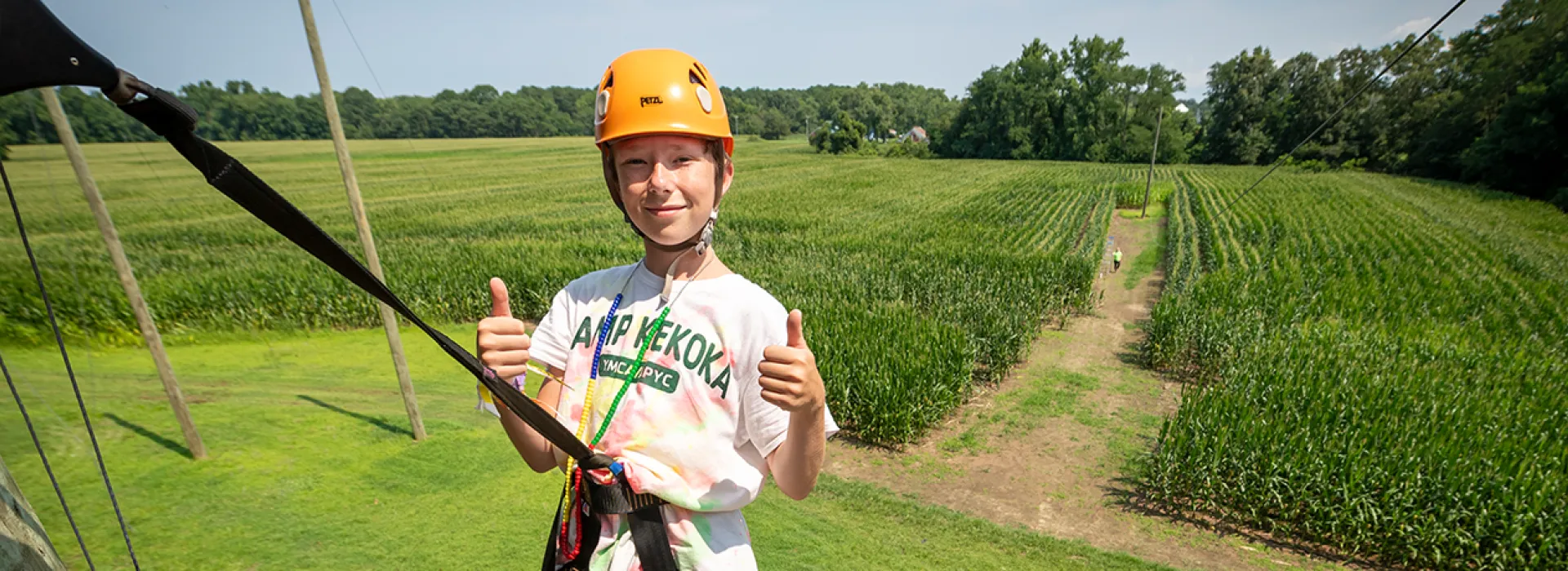 Camper giving a thumbs up at the top of the climbing wall